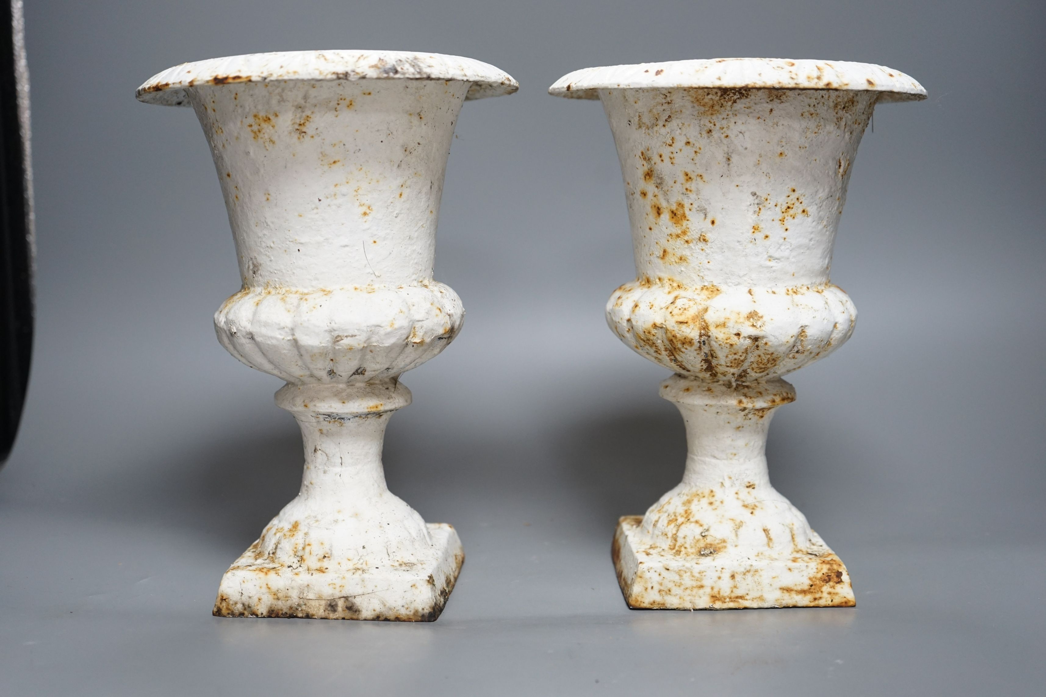 A pair of small white painted cast-iron campana urns, 25cms high